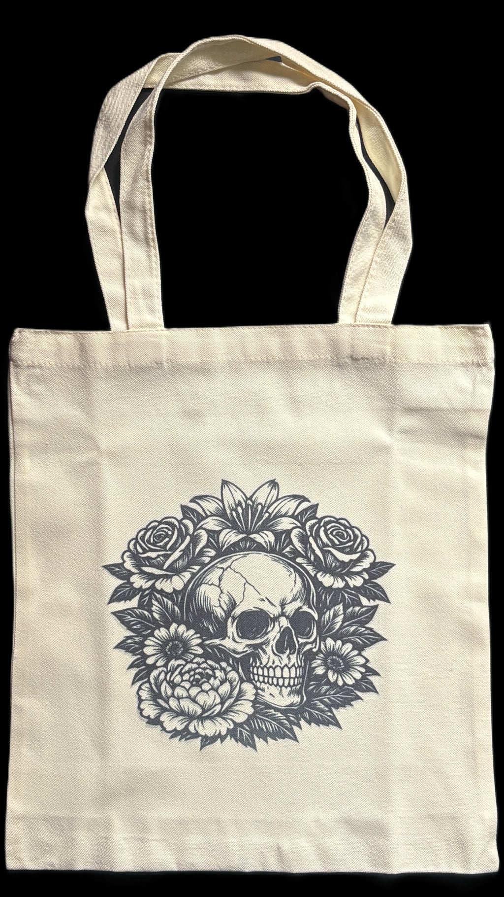 Tote bag with a skull and floral design on a black background