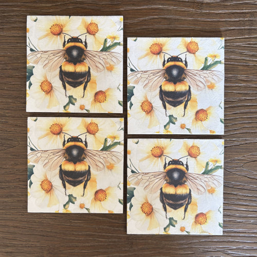Four square magnets featuring a printed design of a bumblebee over yellow flowers, arranged in a 2x2 grid on a dark wood surface.