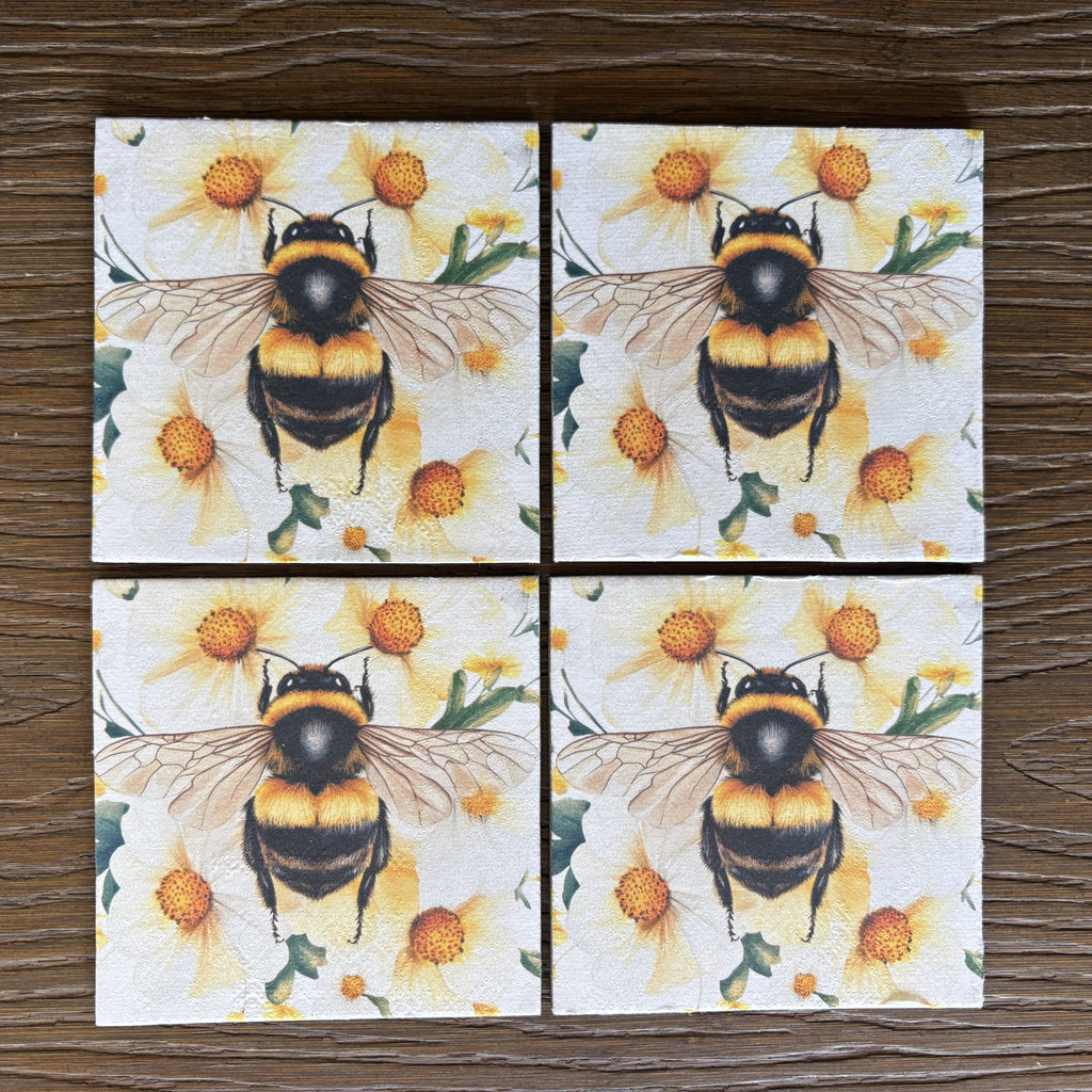 Four square magnets arranged in a 2x2 grid, each printed with a bumblebee over yellow flowers, shown on a dark wood surface.