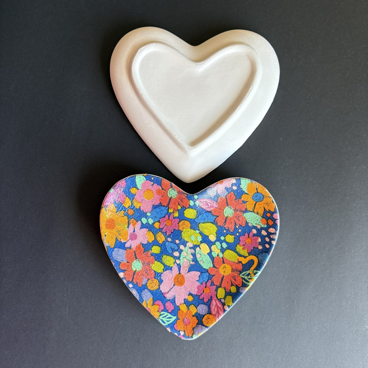 Aa heart-shaped tray or dish with a colorful floral print in blue, pink, orange, yellow, and green. Showing the plan white back of the dish.