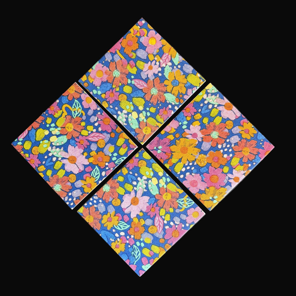 Four square floral magnets arranged in a diamond pattern on a dark gray background. The tiles feature a dense, colorful floral print with pink, orange, yellow, green, and blue flowers on a dark blue base.