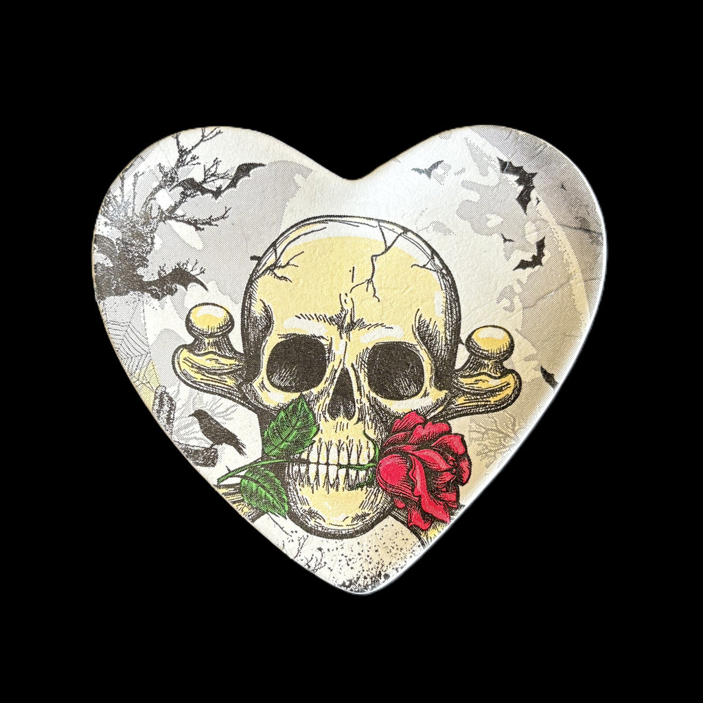 A heart-shaped decorative trinket tray featuring a vintage-style illustration of a skull with a red rose and green leaves, set against a black background.