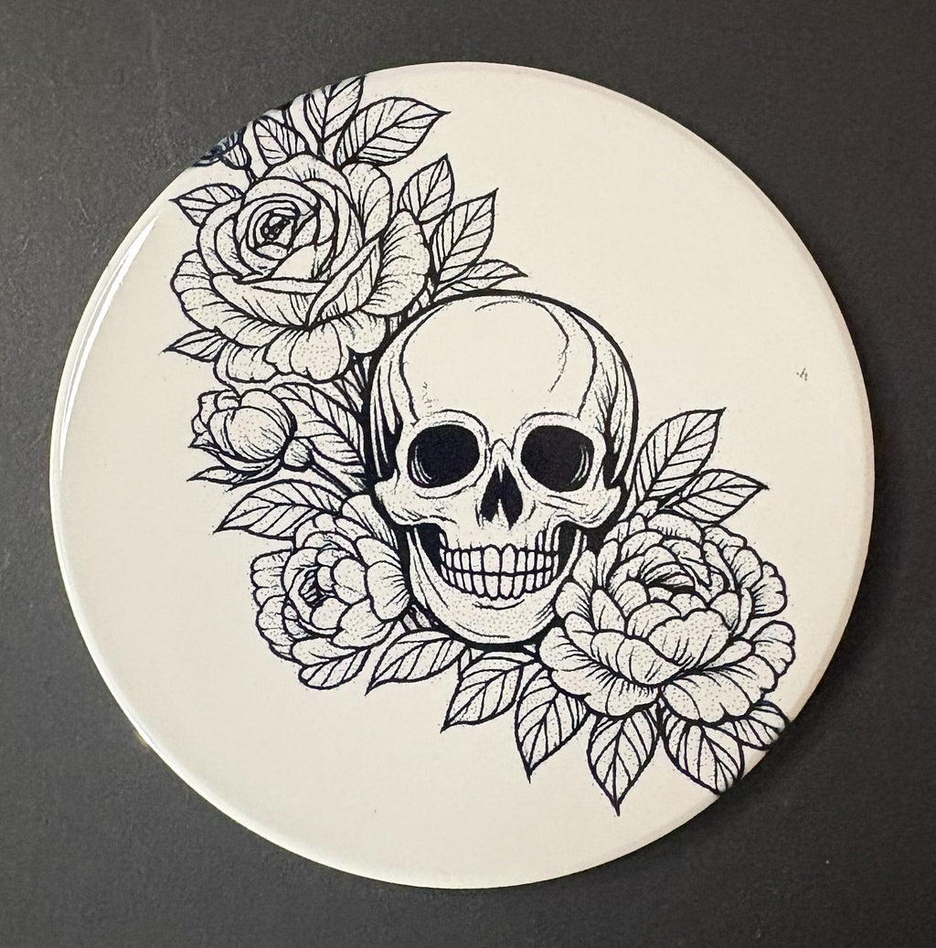 Circular coaster with a black and white skull and floral design on a dark background