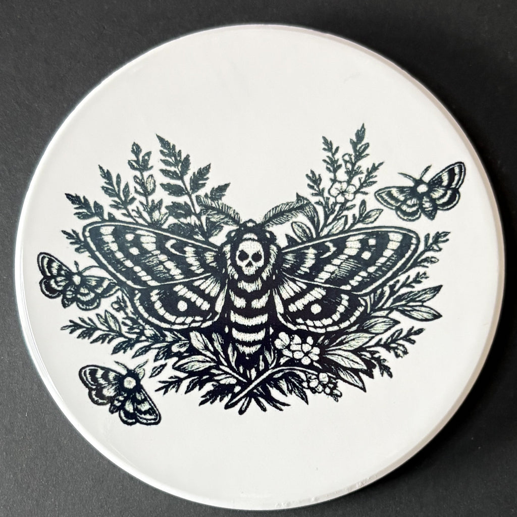Round white plate with black butterfly and floral design on a dark background