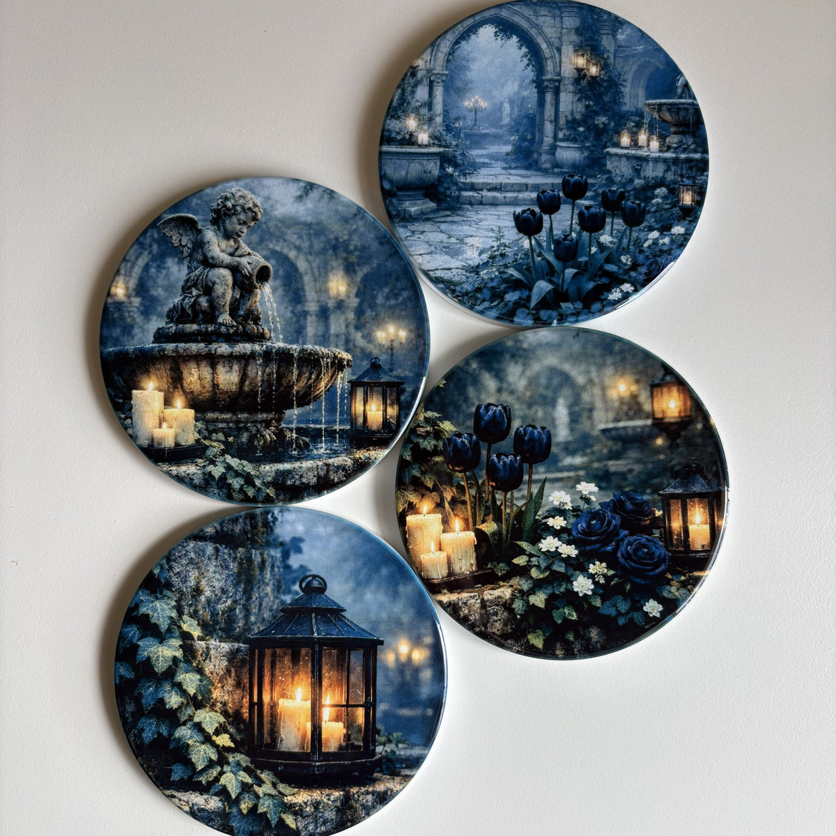 Four round coasters featuring gothic fantasy illustrations of stone fountains, glowing candles, lanterns, and dark blue flowers, arranged on a light neutral background.