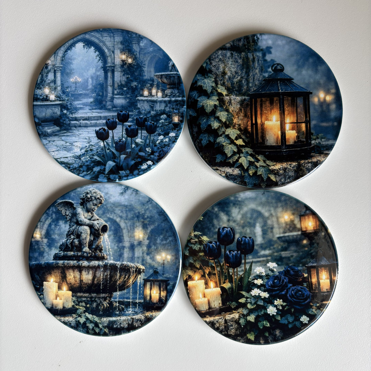 Four round decorative coasters featuring gothic garden scenes in blue and black tones, including a fountain, lanterns, candles, and dark flowers, arranged in a 2x2 grid on a light background.