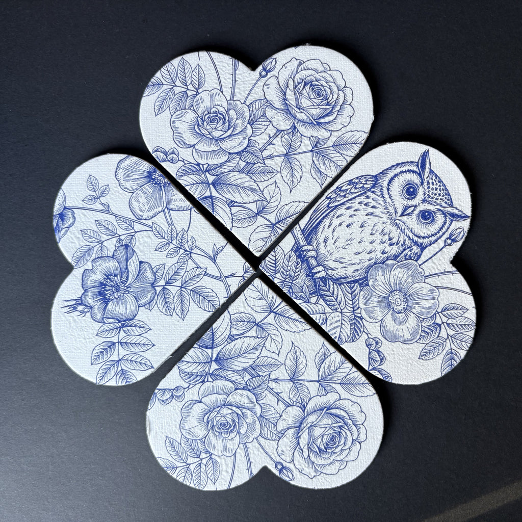 A four-piece set of magnets arranged in a flower shape, featuring a blue and white floral print with roses, leaves, and an owl on a dark background.