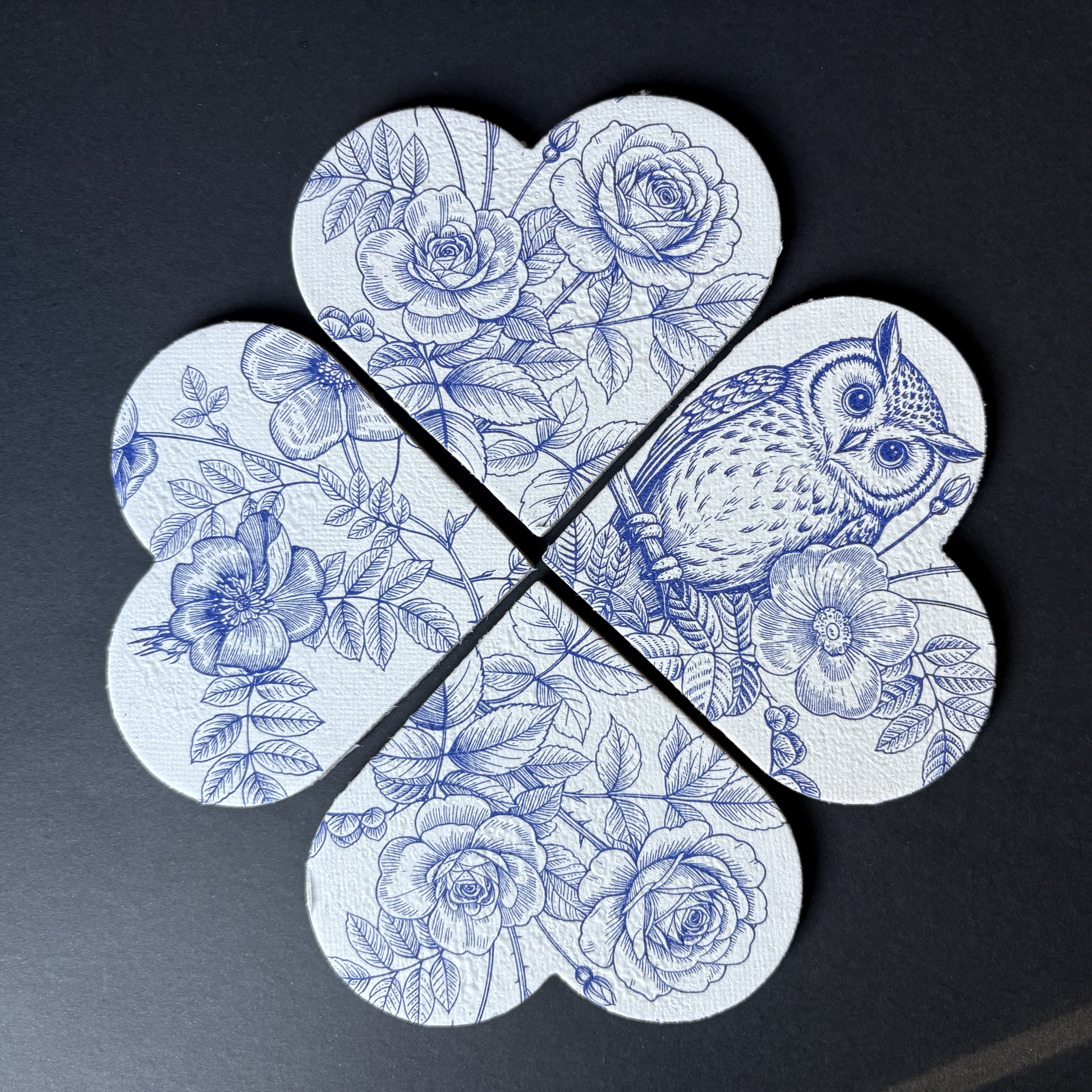 A four-piece set of magnets arranged in a flower shape, featuring a blue and white floral print with roses, leaves, and an owl on a dark background.