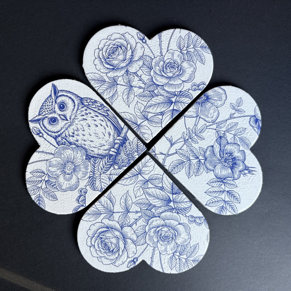 A four-piece set of magnets arranged in a flower shape, featuring a blue and white floral print with roses, leaves, and an owl on a dark background.