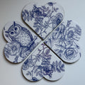 Four heart-shaped magnets with blue floral and owl illustrations on a white background, arranged on a dark surface.