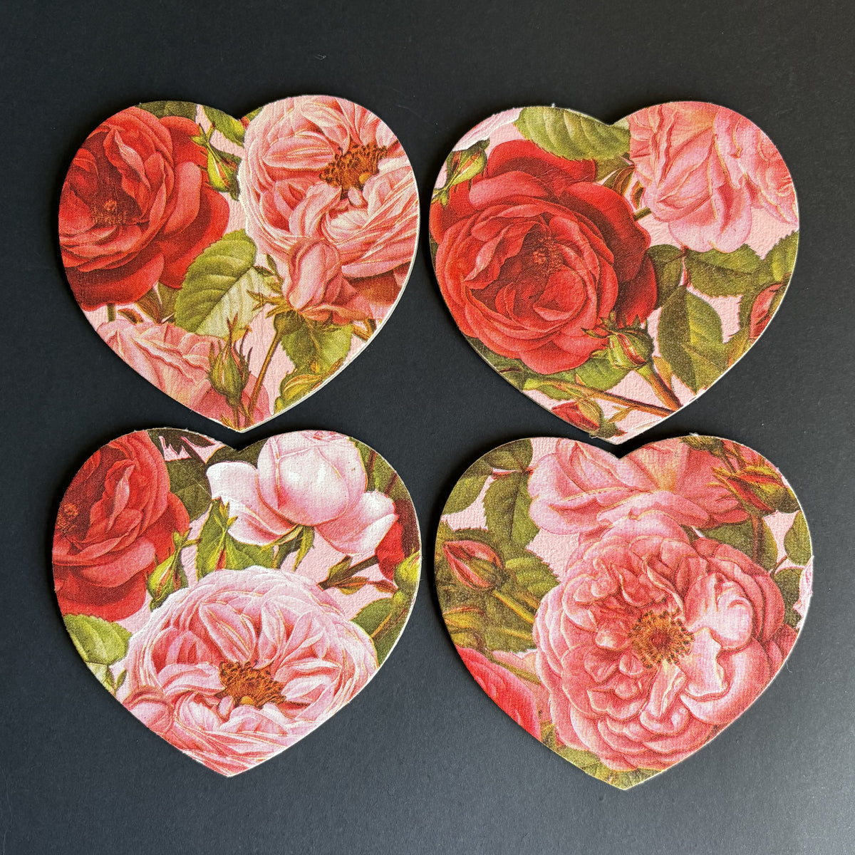 Four heart-shaped magnets arranged in a 2x2 grid on a dark gray background, each featuring a vintage floral print with red and pink roses and green leaves.