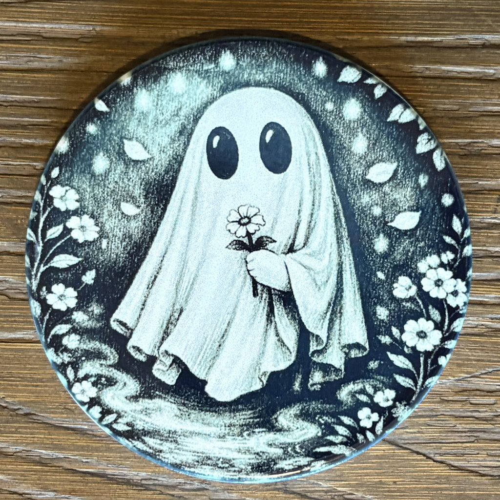 A round decorative plate featuring a black and white illustration of a ghost holding a flower, set on a wooden surface.