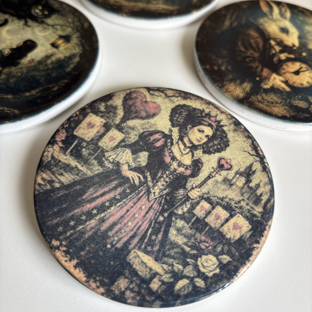 A close-up of a round printed coaster or magnet featuring an illustrated vintage scene with a woman in a dark dress and roses, with other similar round items partially visible around it on a white surface.