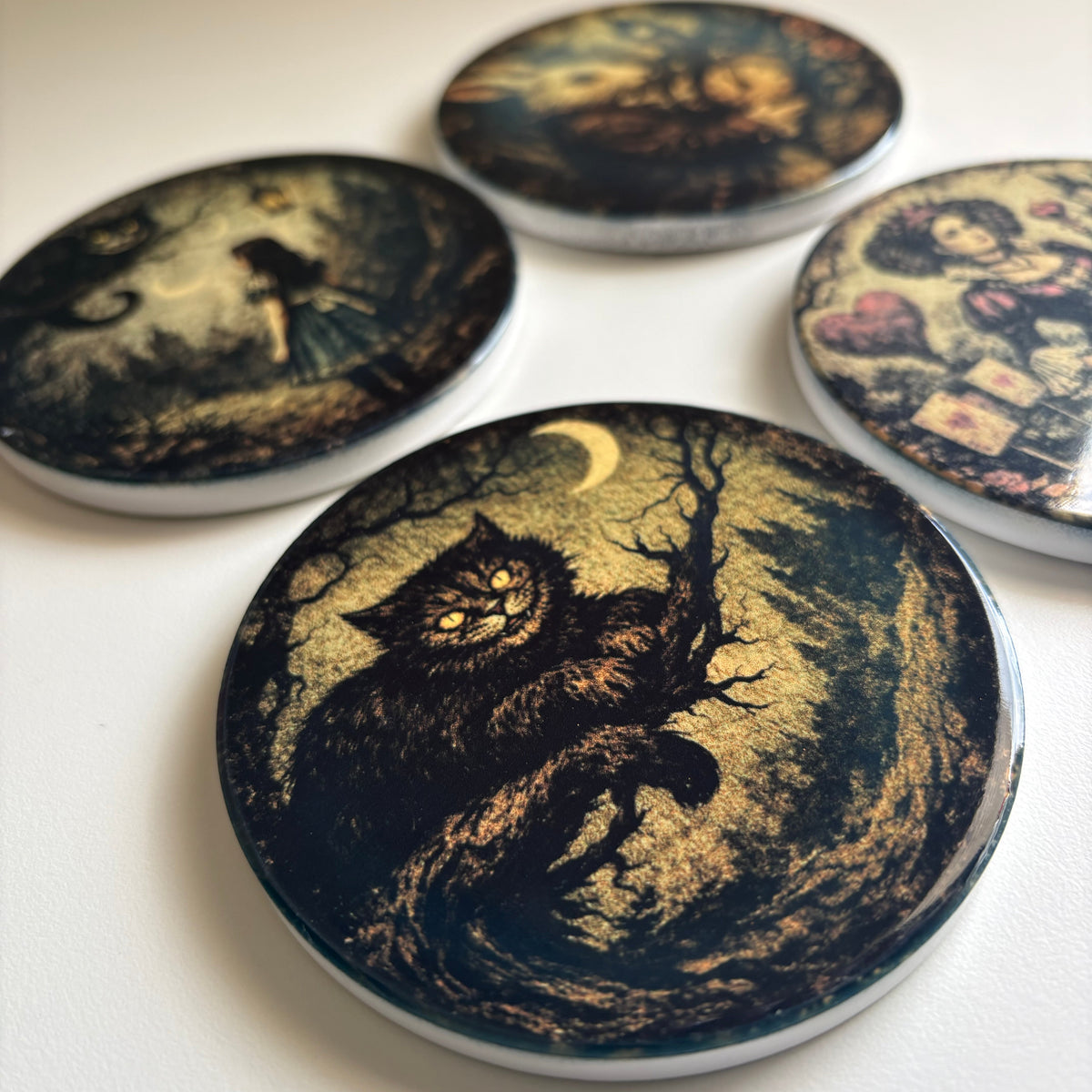Four round printed coasters or magnets with whimsical illustrated scenes, arranged on a light neutral surface. The front piece is most prominent and shows a dark cat under a crescent moon in a moonlit scene.