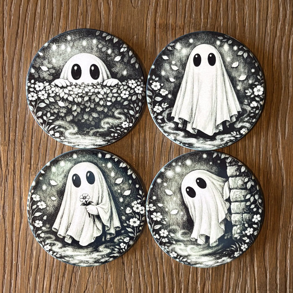 Four round coasters featuring black and white ghost illustrations in different poses, arranged in a 2x2 grid on a wooden surface.