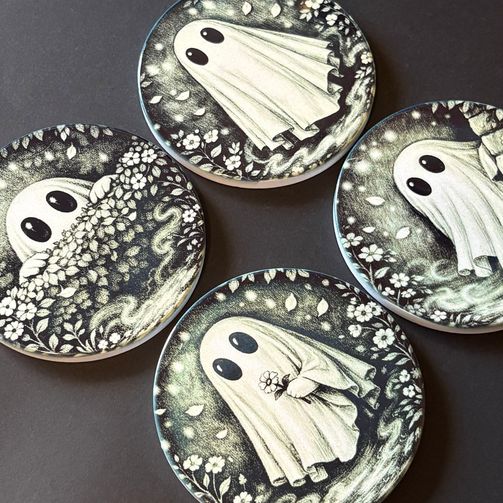 Four round coasters featuring a gothic-style illustration of a white ghost surrounded by black and gray floral patterns, arranged on a dark surface.