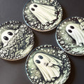 Four round coasters featuring a gothic-style illustration of a white ghost surrounded by black and gray floral patterns, arranged on a dark surface.