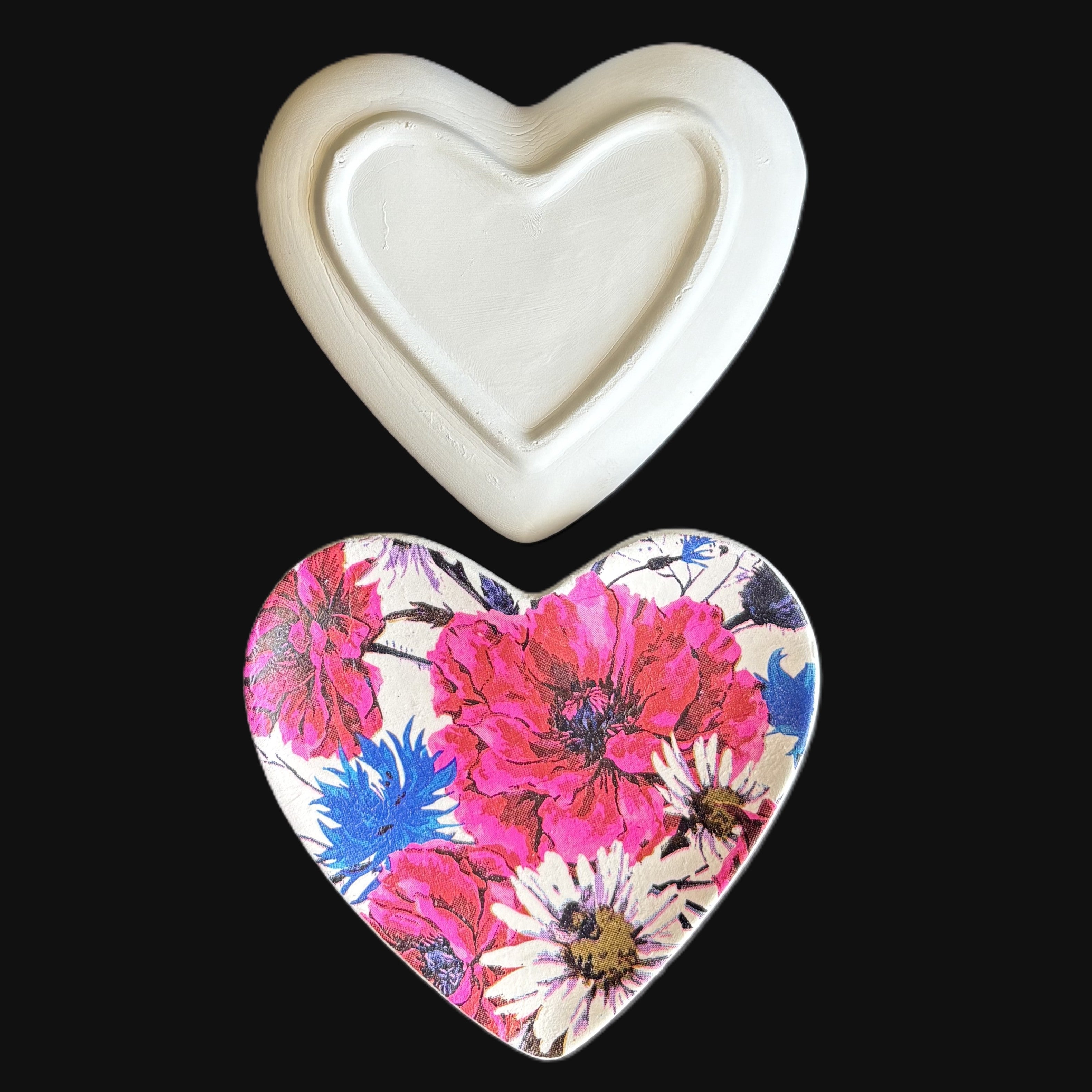 A heart-shaped product shown in two views against a black background: an off-white molded back piece at the top and a floral front piece at the bottom featuring large pink flowers, blue accents, and white daisy-like centers.