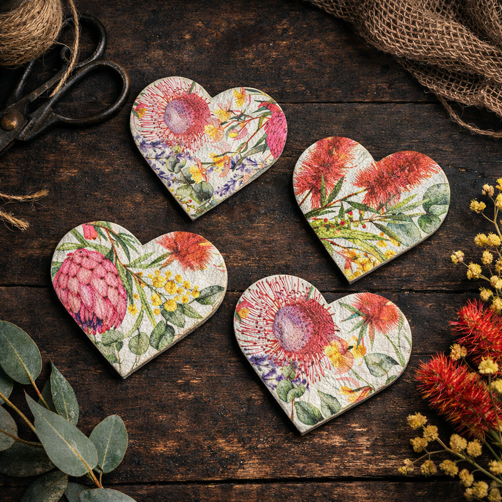 Four heart-shaped magnets with a vintage floral print, arranged on a dark rustic wooden tabletop with decorative props like scissors, burlap, and dried flowers.