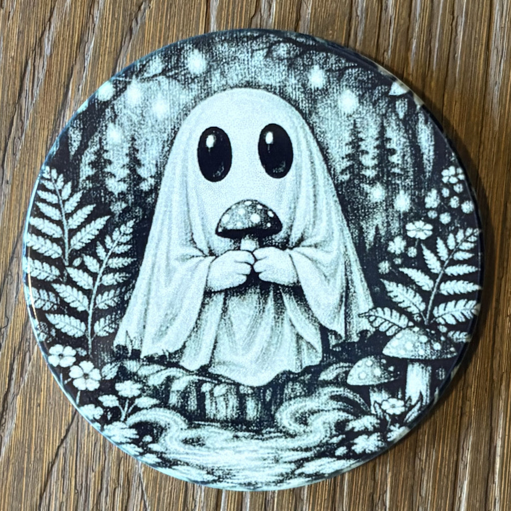 A round coaster featuring a black and white illustration of a cute ghost character holding a mushroom in a forest setting, placed on a wooden surface.