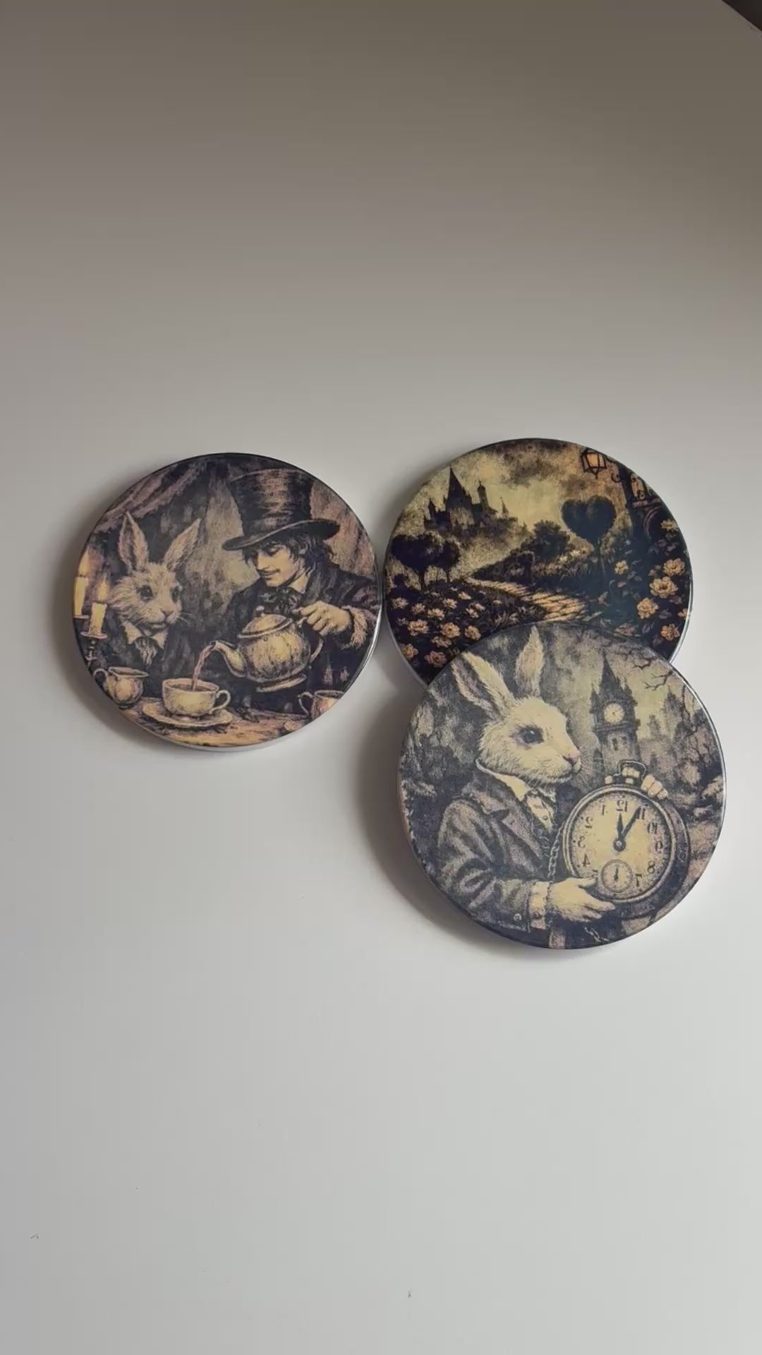 Four round coasters with vintage-style black and sepia illustrations of rabbits, a clock, a woman and rabbit, and a landscape path. 